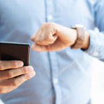 Closeup of business man holding smartphone and checking time
